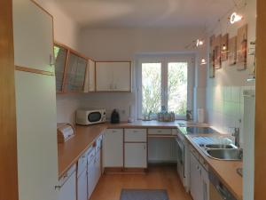 kuchnia z białymi szafkami i zlewem w obiekcie FAMILY APARTMENT LINZ Wohnen mit Garten am Fusse des Pöstlingbergs TOP LAGE Villenviertel w Linzu