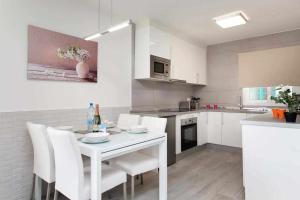 biała kuchnia z białym stołem i krzesłami w obiekcie Apartamento Coral Bay II by Vacanzy Collection w Corralejo