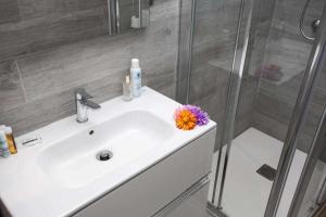 w łazience znajduje się umywalka z prysznicem i kwiatem w obiekcie Apartamento Coral Bay II by Vacanzy Collection w Corralejo +8 zdjęć