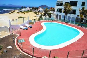basen obok plaży i budynku w obiekcie Apartamento Coral Bay II by Vacanzy Collection w Corralejo