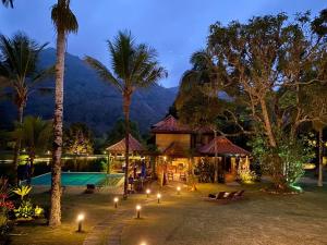 a resort with a swimming pool and palm trees at night at Pousada Parador Santarém in Itaipava