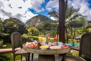 a table with food and drinks on a balcony with mountains at Pousada Parador Santarém in Itaipava