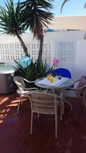 uma mesa e cadeiras num pátio com palmeiras em Apartamento Perseo em Corralejo