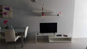 a living room with a television and a table with chairs at Apartamento Perseo in Corralejo