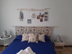 ein Schlafzimmer mit einem blauen Bett mit blauen Laken und Bildern an der Wand in der Unterkunft Al giardino Sant'Anna in Mascali