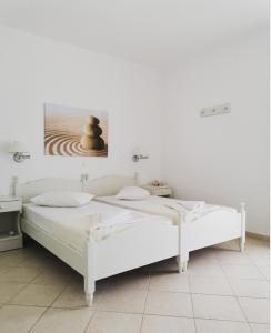 2 camas en una habitación blanca con una foto en la pared en Aegeo Inn Apartments en Antiparos Town
