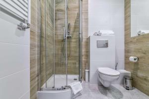 a bathroom with a toilet, sink, and shower stall at LTC Apartments Haffnera in Sopot