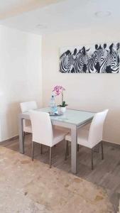 uma sala de jantar com uma mesa e cadeiras brancas em Apartamento Ocean em Corralejo