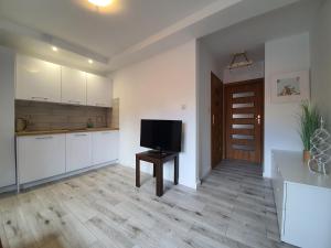 a kitchen with white cabinets and a flat screen tv at Pensjonat Amber in Pobierowo