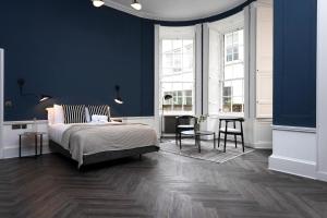 a bedroom with blue walls and a bed and a table at 29 Queen Street Aparthotel in Edinburgh