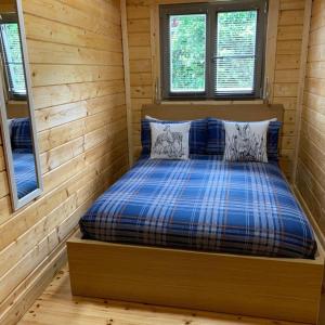 a bed in a log cabin with two windows at Immaculate Cabin 5 mins to Inverness Dog friendly in Inverness