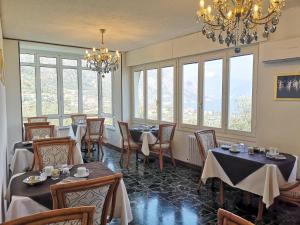 a dining room with tables and chairs and windows at Hotel Villa Margherita in Limone sul Garda