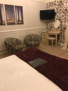 a bedroom with a bed and chairs and a desk at Lauriston & Lawton Court Hotel in Llandudno