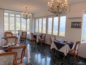 a dining room with tables and chairs and windows at Hotel Villa Margherita in Limone sul Garda