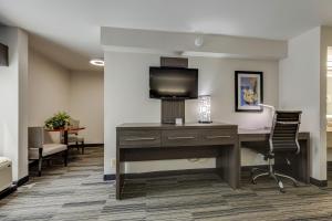an office with a desk and a tv on a wall at Alexis Inn and Suites Hotel in Nashville