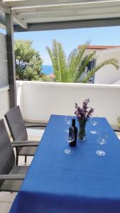 a blue table with wine glasses and flowers on a patio at Apartments Riba in Vis