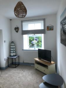 uma sala de estar com televisão e janela em Graigfryn em Amlwch