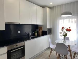 a kitchen with white cabinets and a table with red roses at Ninho Citadino Aveiro in Aveiro