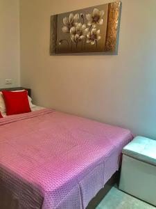 Un dormitorio con una cama rosa y una pintura en la pared. en Nikos Apartament en Prinos