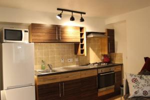a kitchen with wooden cabinets and a white refrigerator at The Snug, a great flat in the heart of Peebles. in Peebles