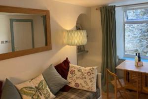 The Snug, a great flat in the heart of Peebles. في بيبلز: غرفة معيشة مع أريكة وطاولة ومرآة