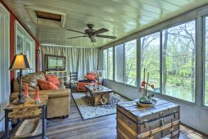a living room with a ceiling fan and large windows at Cozy Cabin with Sunroom and Cacapon River Access! in Capon Bridge