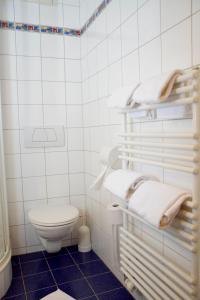 ein weiß gefliestes Bad mit WC und Handtüchern in der Unterkunft Rathskeller Weitra in Weitra