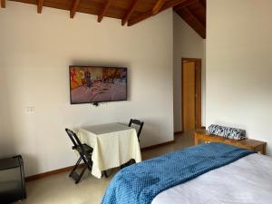 Villaggio da Mata في سانتو أنطونيو دو بينهال: غرفة نوم بسرير وطاولة ودهان على الحائط