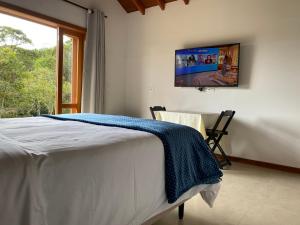 a bedroom with a bed with a tv on the wall at Villaggio da Mata in Santo Antônio do Pinhal