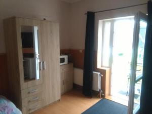 1 dormitorio con armario, microondas y ventana en Muskáti apartman.Hunyadi.ut.6.sz., en Paks