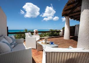 eine Terrasse mit Stühlen, einem Tisch und Meerblick in der Unterkunft Villa Sciacca Lumia in Sciacca