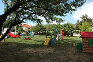 a park with a playground with slides and a tree at Bike and Breakfast Apartments in Pietra Ligure