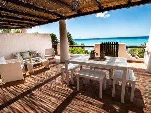 uma mesa branca e cadeiras num deque com praia em Villa Sciacca Lumia em Sciacca