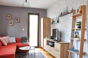 a living room with a red couch and a tv at Apartman SIX Zlatibor in Zlatibor