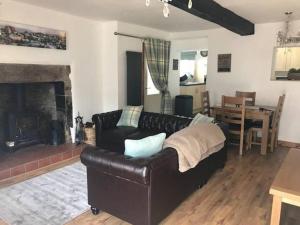 a living room with a leather couch and a fireplace at Old Hall cottage in Hope