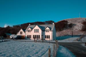 a house in the snow in front of a hill at Hazelbank in Colbost