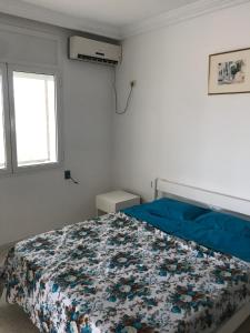 a bedroom with a bed with a blue comforter and a window at Maison dhiefa avec piscine in Temlale