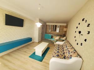 a living room with a couch and a tv on a wall at Апартамент Анели in Pomorie