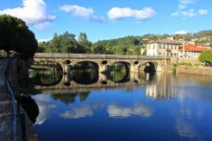a bridge over a river with reflections in the water at Luna Arcos Hotel Nature & Wellness in Arcos de Valdevez