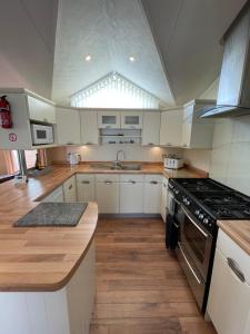 a kitchen with white cabinets and a stove top oven at Torrey Pines - 2 bedroom hot tub lodge with free golf, NO BUGGY in Swarland