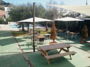una mesa de picnic con sombrillas, mesas y sillas en Apartament L'Estartit - Costa Brava, en Torroella de Montgrí