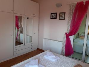 a bedroom with a bed and a window with pink curtains at Palio Villa in Paleo Tsifliki