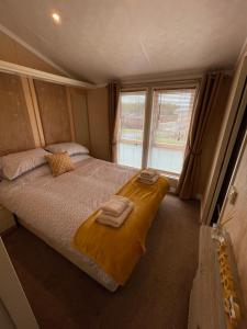 a bedroom with a bed with two towels on it at Torrey Pines - 2 bedroom hot tub lodge with free golf, NO BUGGY in Swarland +32 photos