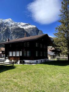 a large brown building with mountains in the background at Familienferien im Chalet Bärgli Kandersteg in Kandersteg