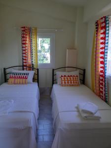 two beds in a room with colorful curtains at Palio Villa in Paleo Tsifliki