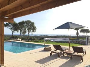 a patio with two chairs and an umbrella and a swimming pool at BINIALMESC in Alaior