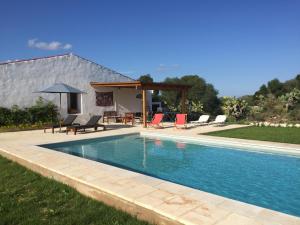 a swimming pool in a yard with chairs and an umbrella at BINIALMESC in Alaior