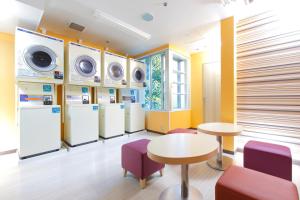 a laundry room with refrigerators and tables and purple chairs at HOTEL MYSTAYS Nagoya Sakae in Nagoya