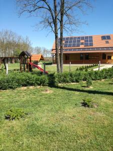 un patio con parque infantil y un edificio con paneles solares en Kaptárlevegős Vendégház, en Füzesgyarmat