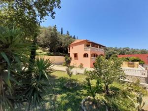 una gran casa rosa con un patio con árboles en Villa Silvia, en Ágios Matthaíos